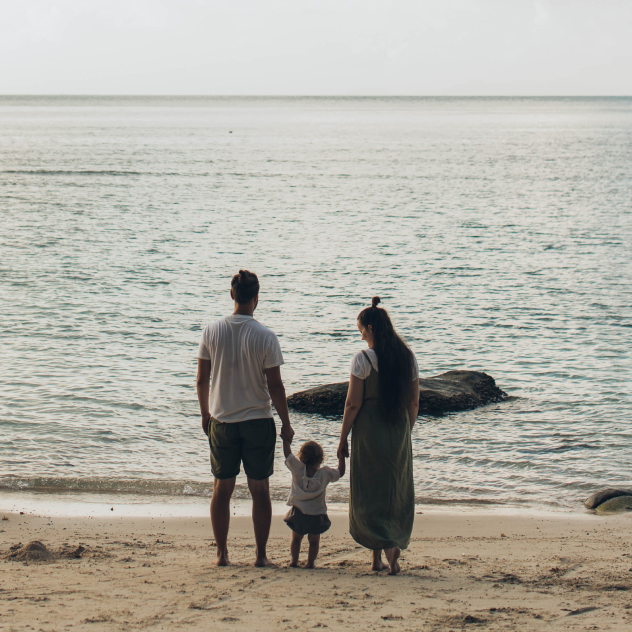 A man and a woman holding hands of their child, symbolizing connection.